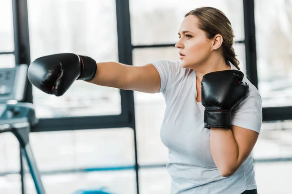 Serious overweight girl practicing kickboxing in gym — Stock Photo