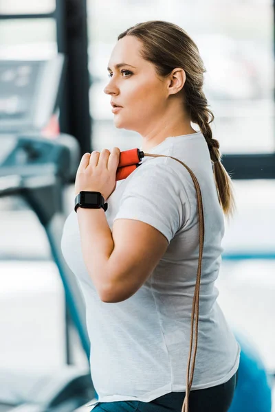 Attractive plus size woman holding jumping rope in gym — Stock Photo