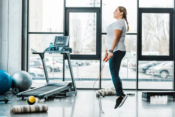 Attrayant plus taille femme exerçant avec corde sautante dans la salle de gym — Photo de stock