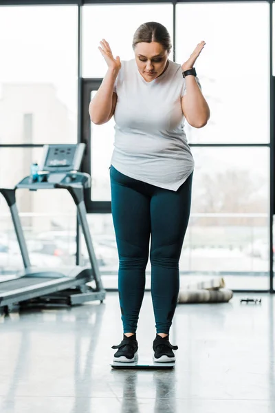 Sorprendida mujer con sobrepeso haciendo gestos mientras está de pie en escamas - foto de stock