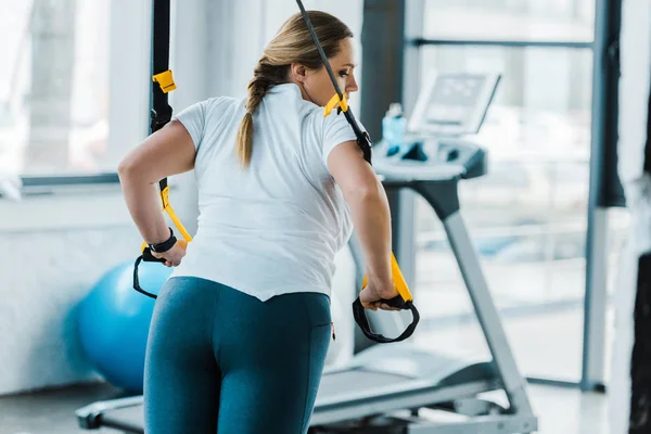 Plus size Mädchen Trainingsarme mit Aufhängebändern im Fitnessstudio — Stockfoto