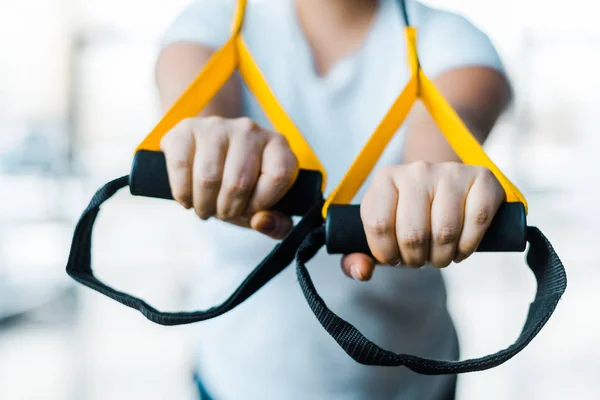 Foco seletivo de braços de treinamento menina plus size com tiras de suspensão no ginásio — Fotografia de Stock