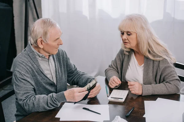 Senior coupe sitting at table with calculator and counting money — стоковое фото