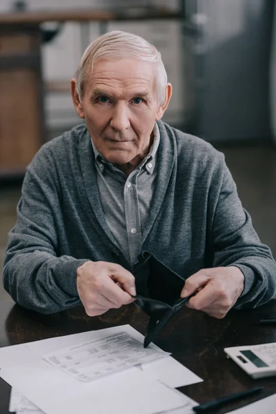 Senior mit leerem Portemonnaie und Blick in Kamera — Stockfoto