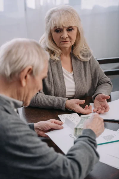 Senior couple having discussion while sitting at table with paperwork — Stock Photo