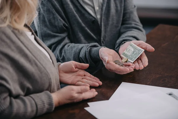 Cropped view of senior couple sitting at table and holding money in hands — Stock Photo