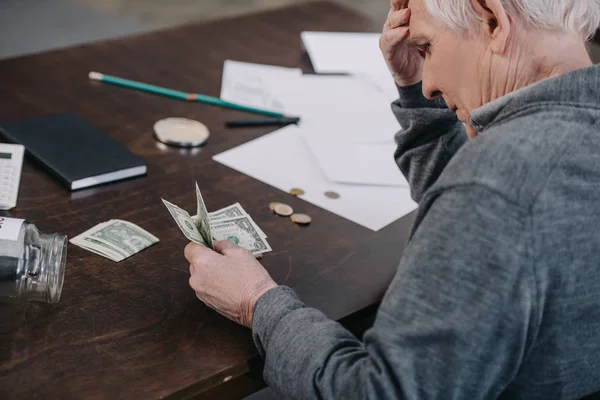 Senior sitzt am Tisch und zählt zu Hause Geld — Stockfoto