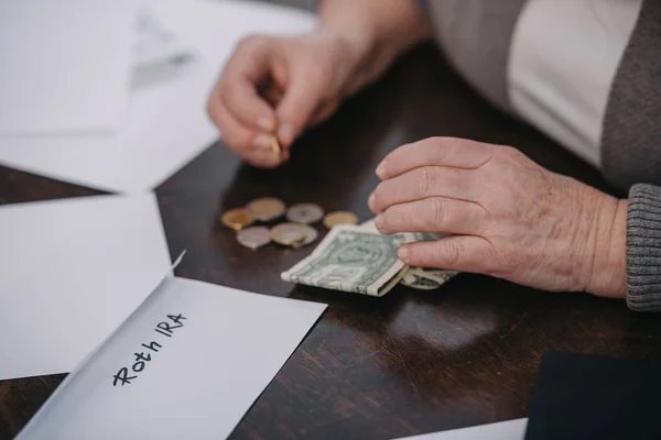 Cropped view of couple woman counting money near envelope with 'roth ira' lettering — Stock Photo