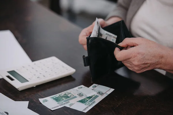 Vista recortada de mujer mayor sosteniendo billetera con dinero - foto de stock