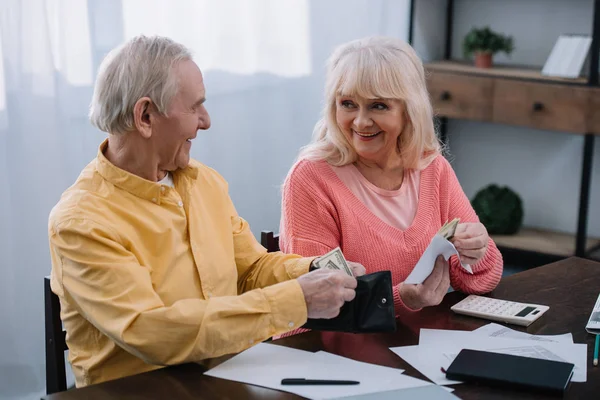 Lächelndes Senioren-Paar mit Geldbörse und Umschlag mit Geld zu Hause — Stockfoto