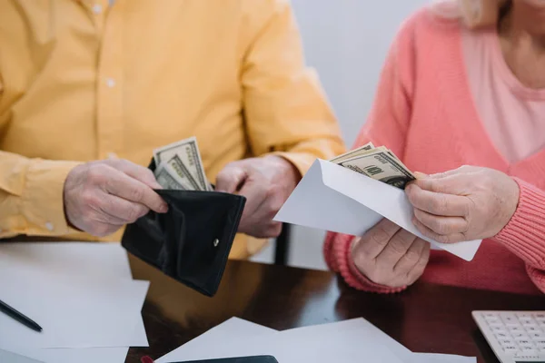 Vue recadrée du portefeuille et de l'enveloppe du couple aîné avec de l'argent — Photo de stock