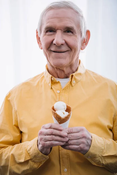 Senior schaut in Kamera und hält Eistüte zu Hause — Stockfoto