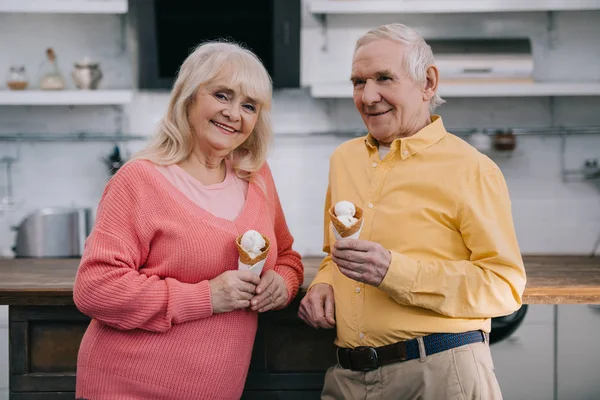 Feliz casal sênior segurando cones de sorvete em casa — Fotografia de Stock