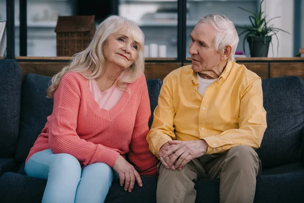 Senior couple in casual clothes sitting on couch in living room — Stock Photo