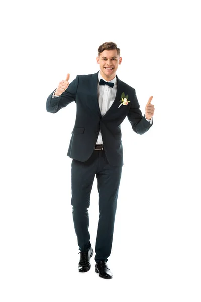 Smiling bridegroom in black suit showing thumbs up isolated on white — Stock Photo