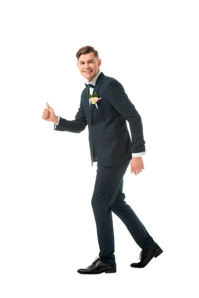 Alegre novio en traje negro mostrando el pulgar hacia arriba aislado en blanco - foto de stock