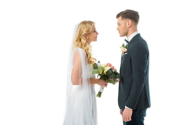 Novia feliz y novio sonriente mirándose aislados en blanco - foto de stock