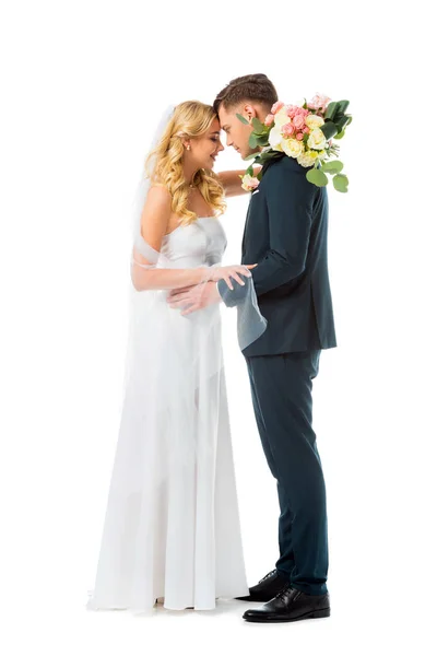 Hübsche Braut im weißen Hochzeitskleid und Bräutigam im eleganten schwarzen Anzug stehen sich von Angesicht zu Angesicht isoliert auf weißem Grund gegenüber — Stockfoto