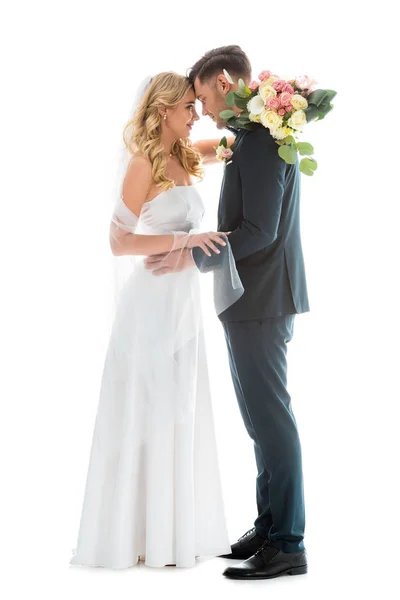 Schöne Braut im weißen Hochzeitskleid und Bräutigam im eleganten schwarzen Anzug stehen sich von Angesicht zu Angesicht isoliert auf weißem Grund gegenüber — Stockfoto