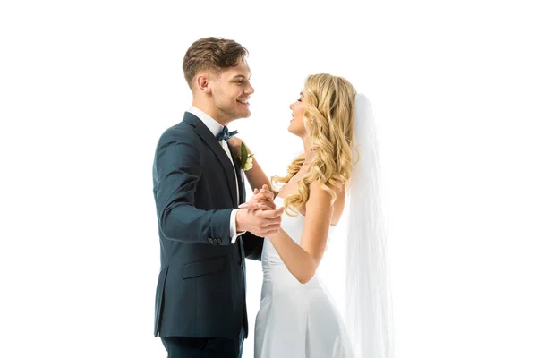 Novia feliz y novio sonriente bailando y mirándose aislados en blanco - foto de stock