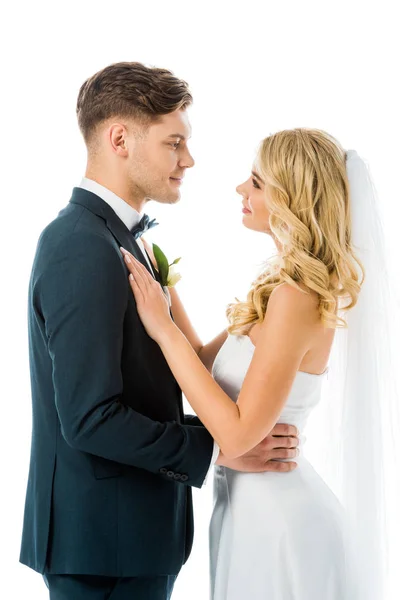 Happy young bride and groom hugging and looking at each other isolated on white — Stock Photo