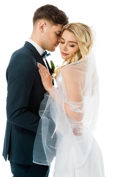 Noiva bonita com os olhos fechados de pé perto do noivo bonito isolado no branco — Fotografia de Stock