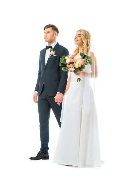 Beautiful bride in long wedding dress holding hands with groom in elegant suit isolated on white — Stock Photo