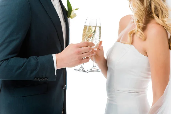 Vista recortada de novia y novio tintineo copas de champán aislado en blanco - foto de stock