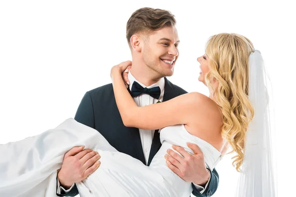 Young groom holding smiling bride on hands isolated on white — Stock Photo