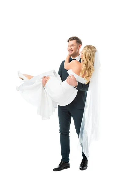 Happy handsome groom holding beautiful bride on hands isolated on white — Stock Photo