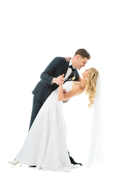 Novio guapo en traje elegante bailando con hermosa novia en vestido de novia aislado en blanco - foto de stock