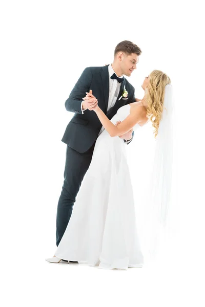 Novio joven en traje elegante bailando con novia feliz aislado en blanco - foto de stock