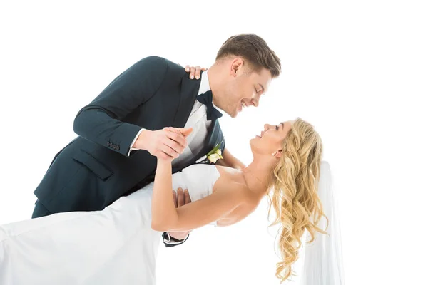 Novio alegre en traje elegante bailando con novia feliz aislado en blanco - foto de stock