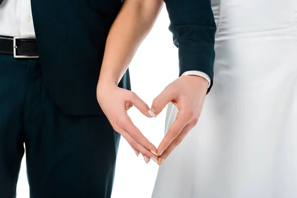 Vista recortada de novia y novio mostrando el signo del corazón con las manos aisladas en blanco - foto de stock