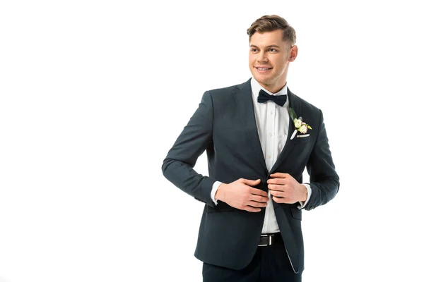 Fröhlicher Bräutigam in eleganter schwarzer Jacke mit Boutonniere isoliert auf Weiß — Stockfoto