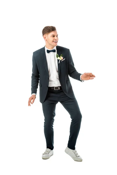 Cheerful groom dancing in black elegant suit and white sneakers isolated on white — Stock Photo