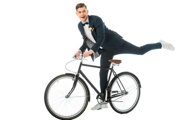 Веселий наречений в елегантному костюмі робить трюки на велосипеді ізольовані на білому — стокове фото