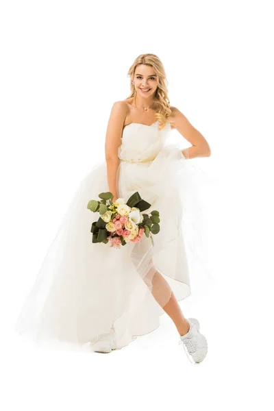 Jovem atraente posando em vestido de noiva e tênis isolado no branco — Fotografia de Stock