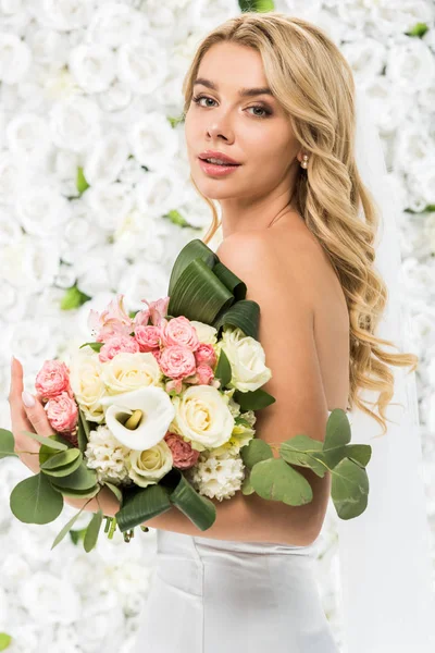 Atractiva mujer joven con ramo de boda sobre fondo floral blanco - foto de stock