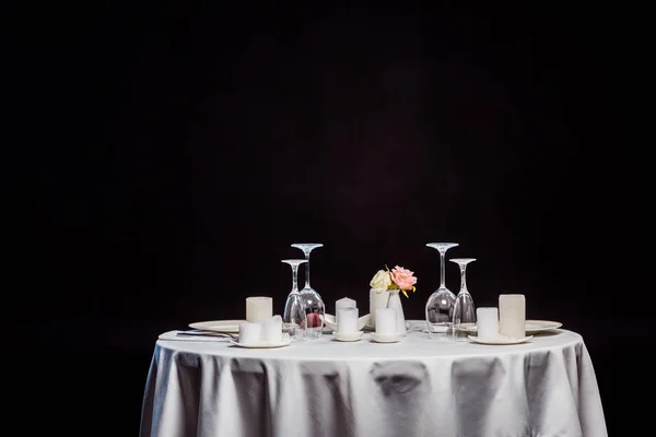 Tavola con tovaglia bianca, stoviglie e candele isolate su nero — Foto stock