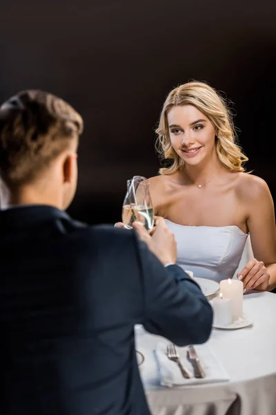 Selektiver Fokus der schönen Braut und des Bräutigams, die Champagnergläser auf schwarzem Hintergrund klirren — Stockfoto