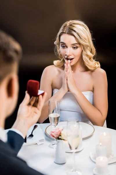 Foco seletivo do homem fazendo proposta de casamento para menina surpresa no fundo preto — Fotografia de Stock