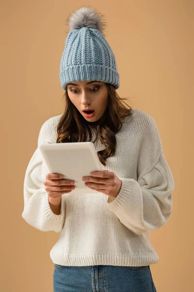 Shocked brunette young woman looking at digital tablet with open mouth isolated on beige — Stock Photo