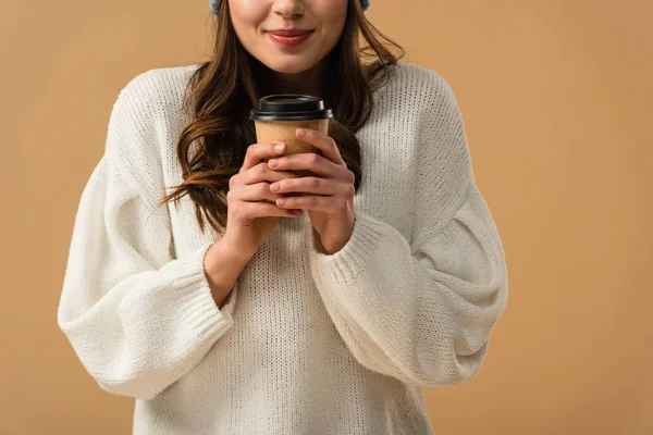 Cropped view of curly brunette girl holding cup of coffee with smile isolated on beige — Stock Photo