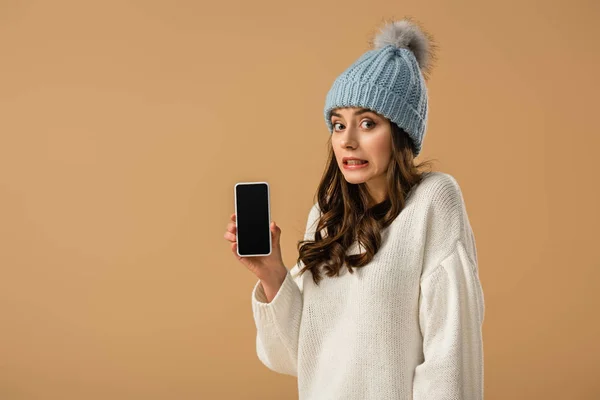 Charming confused girl holding smartphone with blank screen isolated on beige — Stock Photo