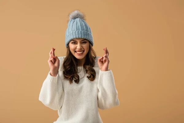 Riéndose rizada joven mujer mostrando cruzados dedos aislados en beige — Stock Photo