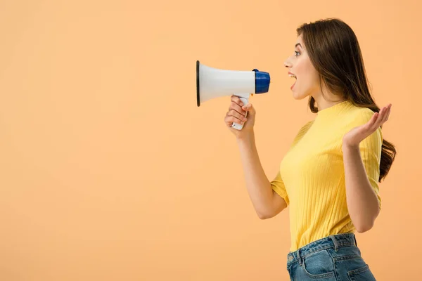 Side view of pretty brunette woman screaming in loudspeaker isolated on orange — Stock Photo