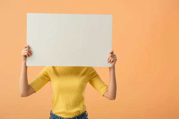 Young woman in yellow jumper holding blank placard isolated on orange — Stock Photo