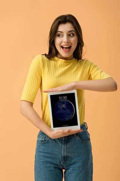 Allegro ragazza bruna con tablet digitale con schermo di blocco isolato su arancione — Foto stock