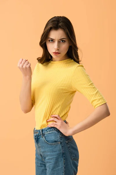 Angry young woman standing with hand on hip isolated on orange — Stock Photo
